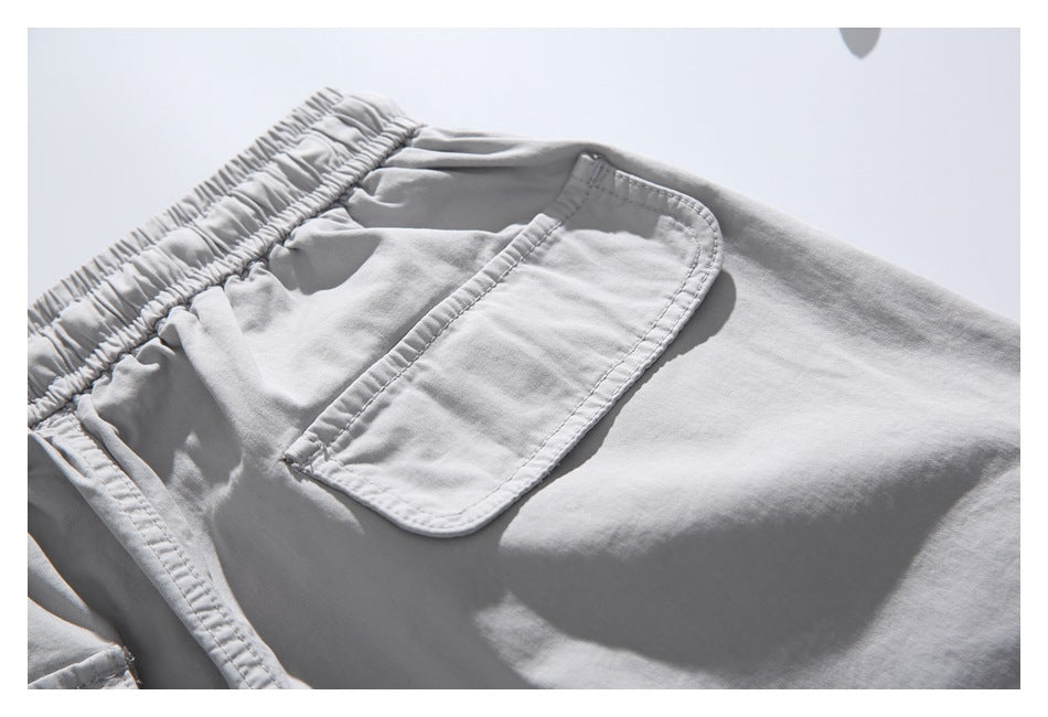 Close-up of a light gray garment showing an elastic waistband and a stitched rectangular pocket.