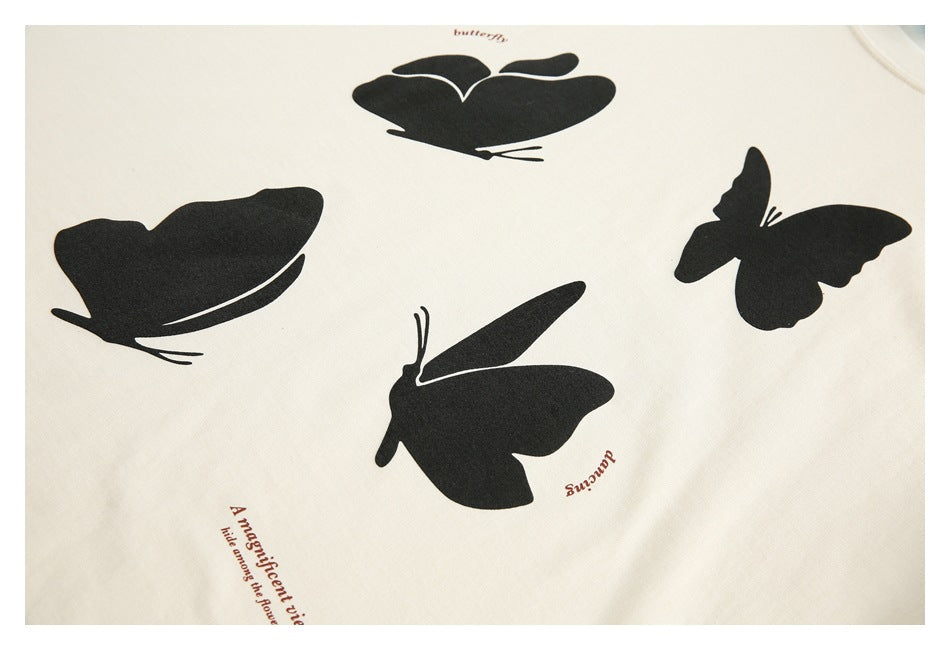 Close-up of black butterfly prints and small brown English text on cream shirt fabric.