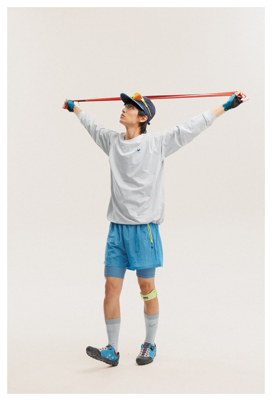 Model wearing a light gray long-sleeve shirt and bright blue shorts over fitted blue shorts.