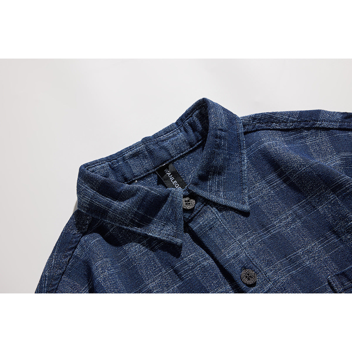 Close-up of a blue plaid shirt collar with dark buttons and a black neck label.