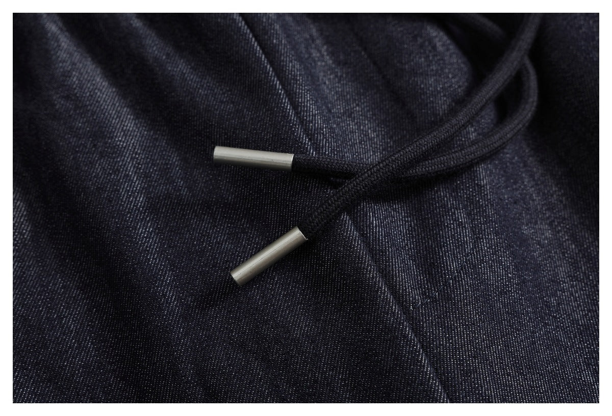 Close-up of dark drawstring cords with metal tips against dark indigo pants.