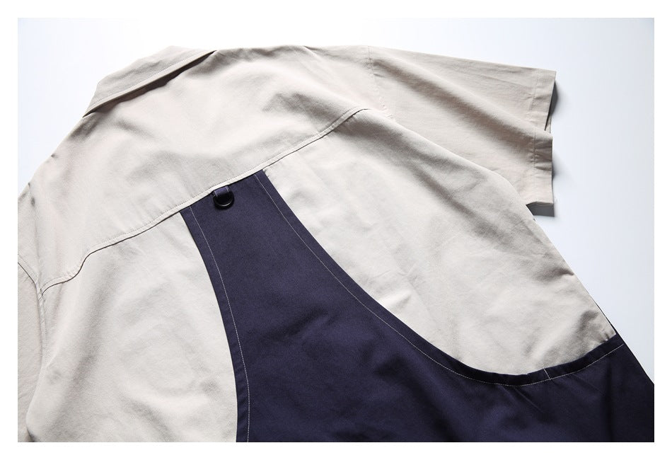 Close-up of a light beige shirt with a curved navy panel, visible stitching, and a black button.