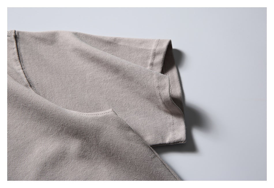 Close-up of a taupe-gray T-shirt shoulder and short sleeve with visible stitching.