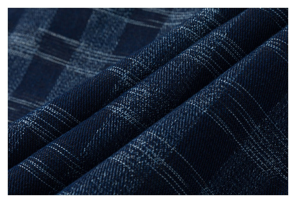 Macro view of dark blue plaid fabric with fine light-colored intersecting lines.