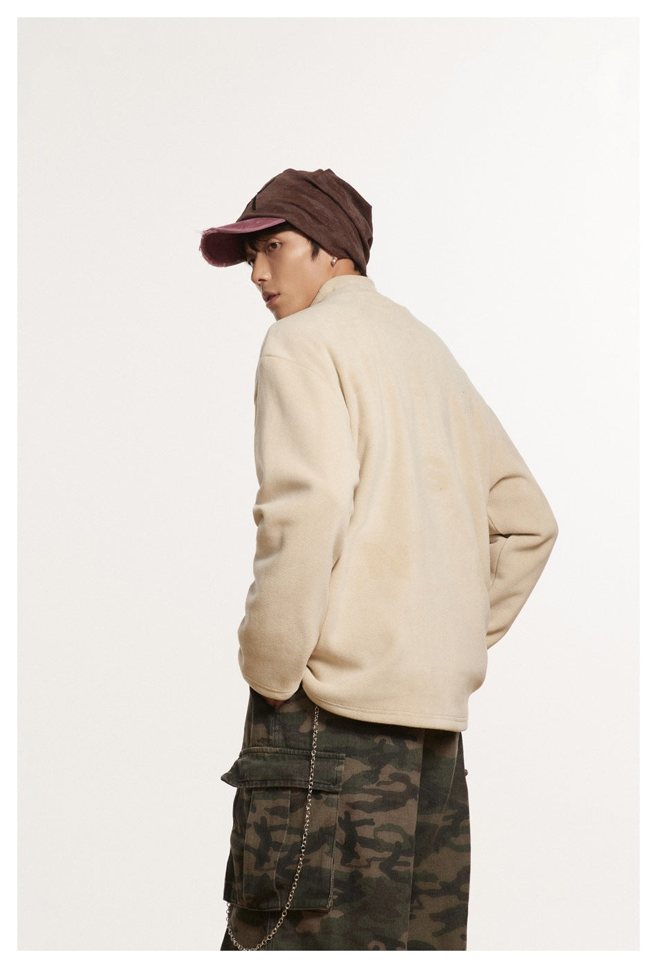 Model wearing a cream pullover and camouflage cargo pants, turned to show the back and side.