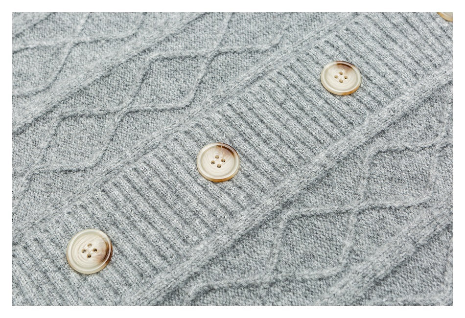 Close-up of a gray cable-knit cardigan front with three light-colored buttons.
