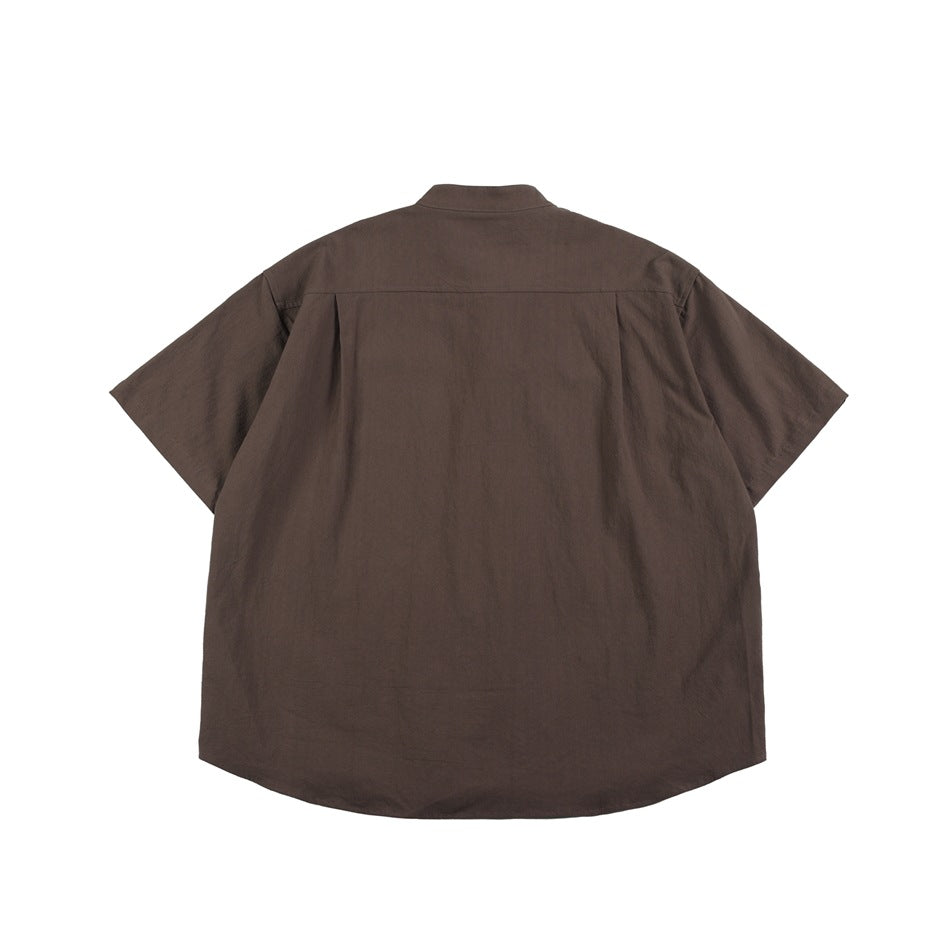 Back view of a brown short-sleeve stand-collar shirt showing the yoke seam, center pleat and curved hem