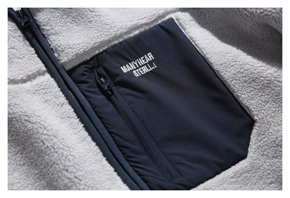 Close-up of a navy zip chest pocket on the gray sherpa jacket, with small white lettering.