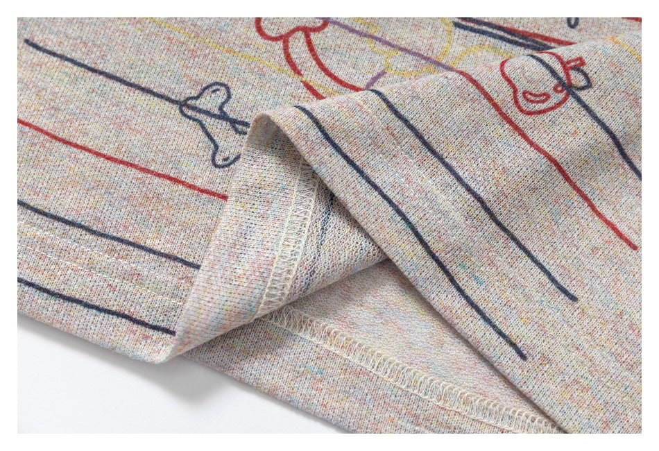 Close-up of the garment's folded, stitched hem with multicolor stripes and outlined doodle prints.