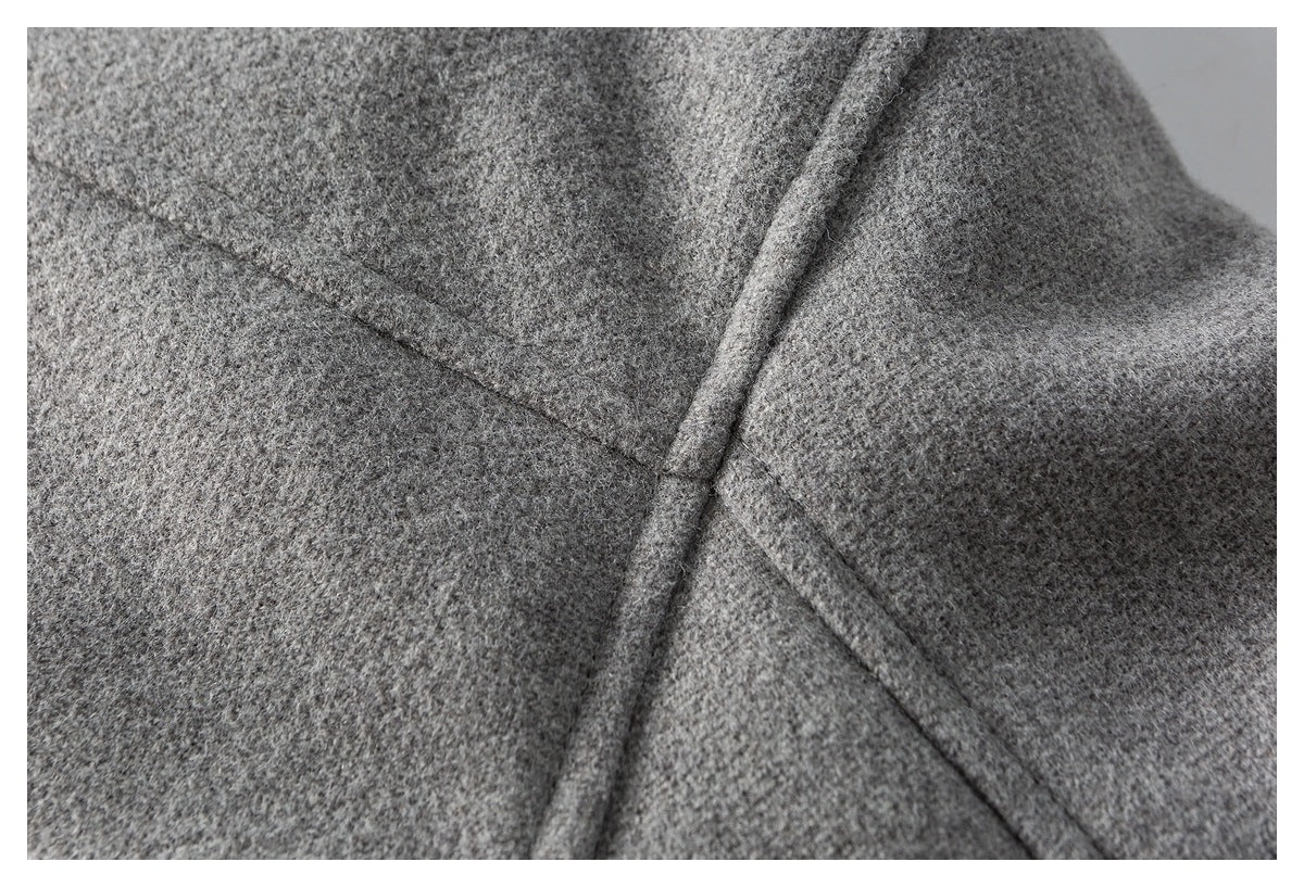 Close-up of gray fabric with intersecting stitched seams and a raised folded edge.