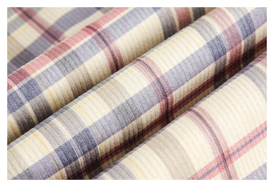 Close-up of folded cream plaid fabric with muted blue-gray, pink, brown, and yellow stripes.