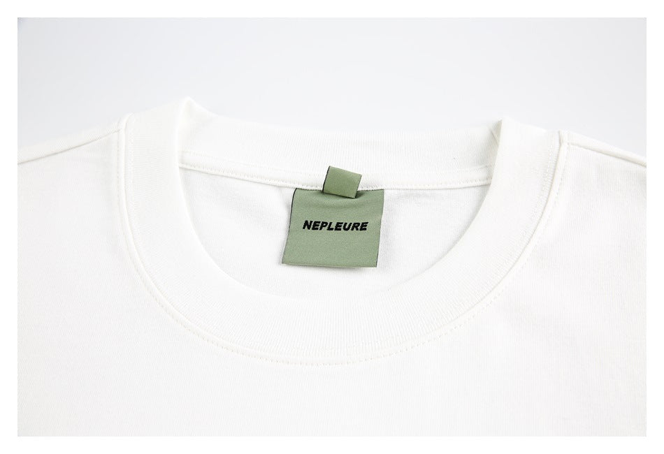 Close-up of a white T-shirt crew neckline with a green neck label.
