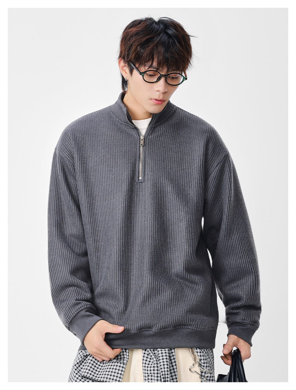 Model wearing a charcoal gray textured quarter-zip sweater with a high collar, ribbed cuffs and hem.
