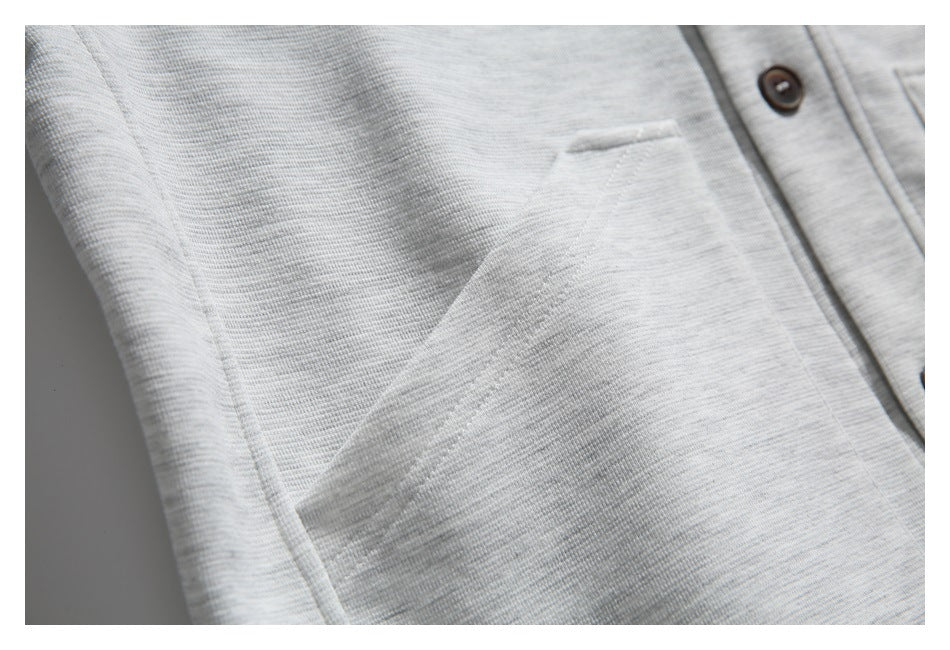 Close-up of the light gray sweatshirt's patch pocket and fine heathered knit texture.