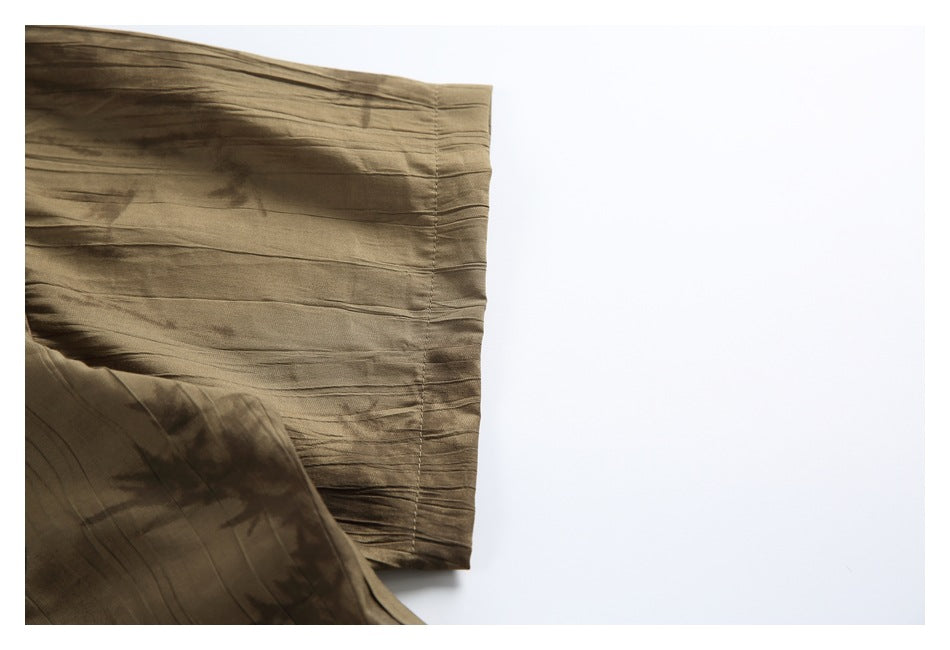 Close-up of the cuff of a brown abstract-patterned shirt against a white background.