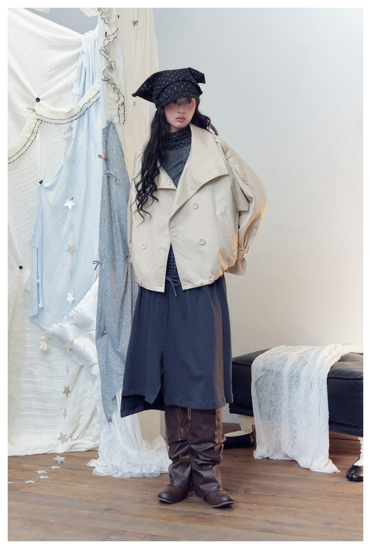 Model in a cream cropped double-breasted jacket with wide collar, posed with a hand behind her, styled with navy skirt