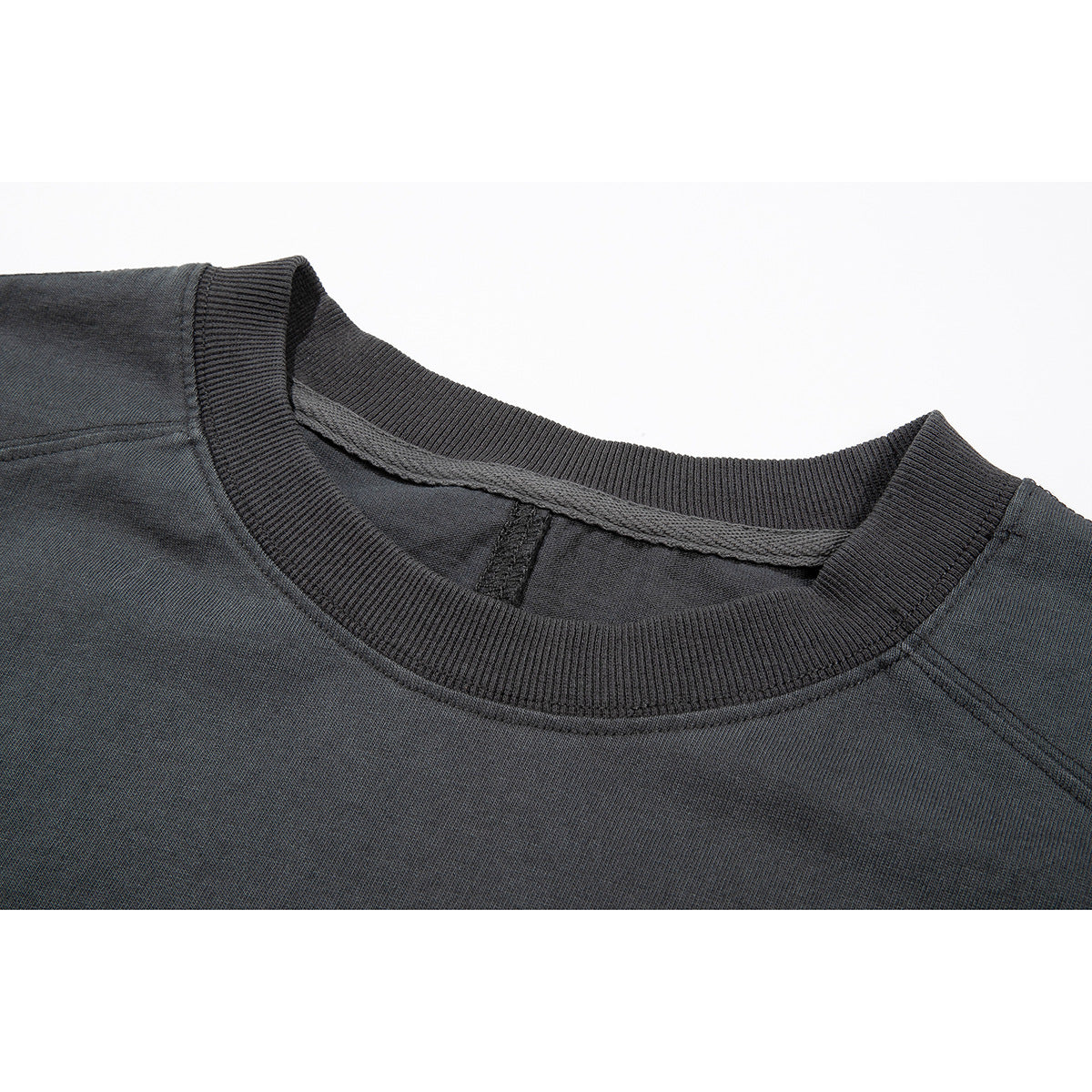Close-up of a charcoal garment's ribbed crew neckline, shoulder seams and inner neck binding.