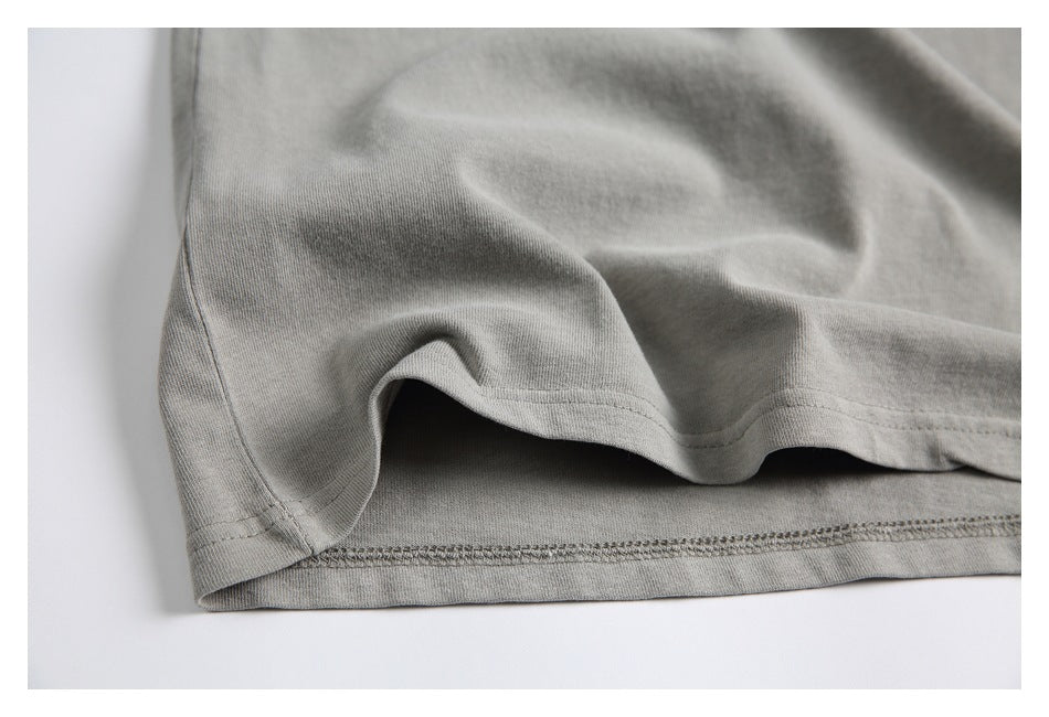Close-up of a light gray garment's side seam and double-stitched lower hem.