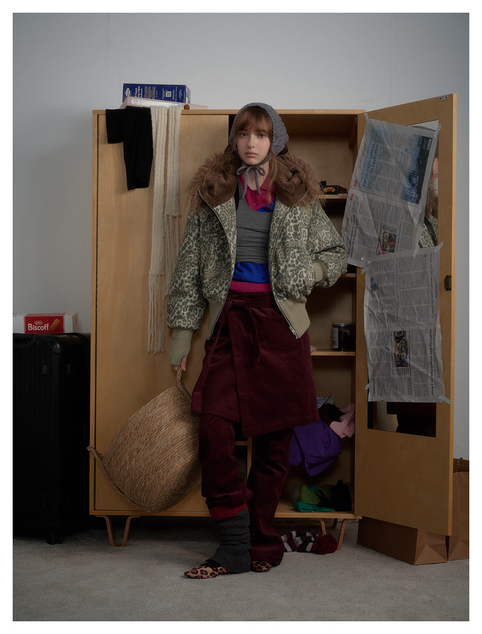 Model facing forward in the leopard print hooded zip jacket with ribbed cuffs, styled with a gray bonnet and burgundy skirt