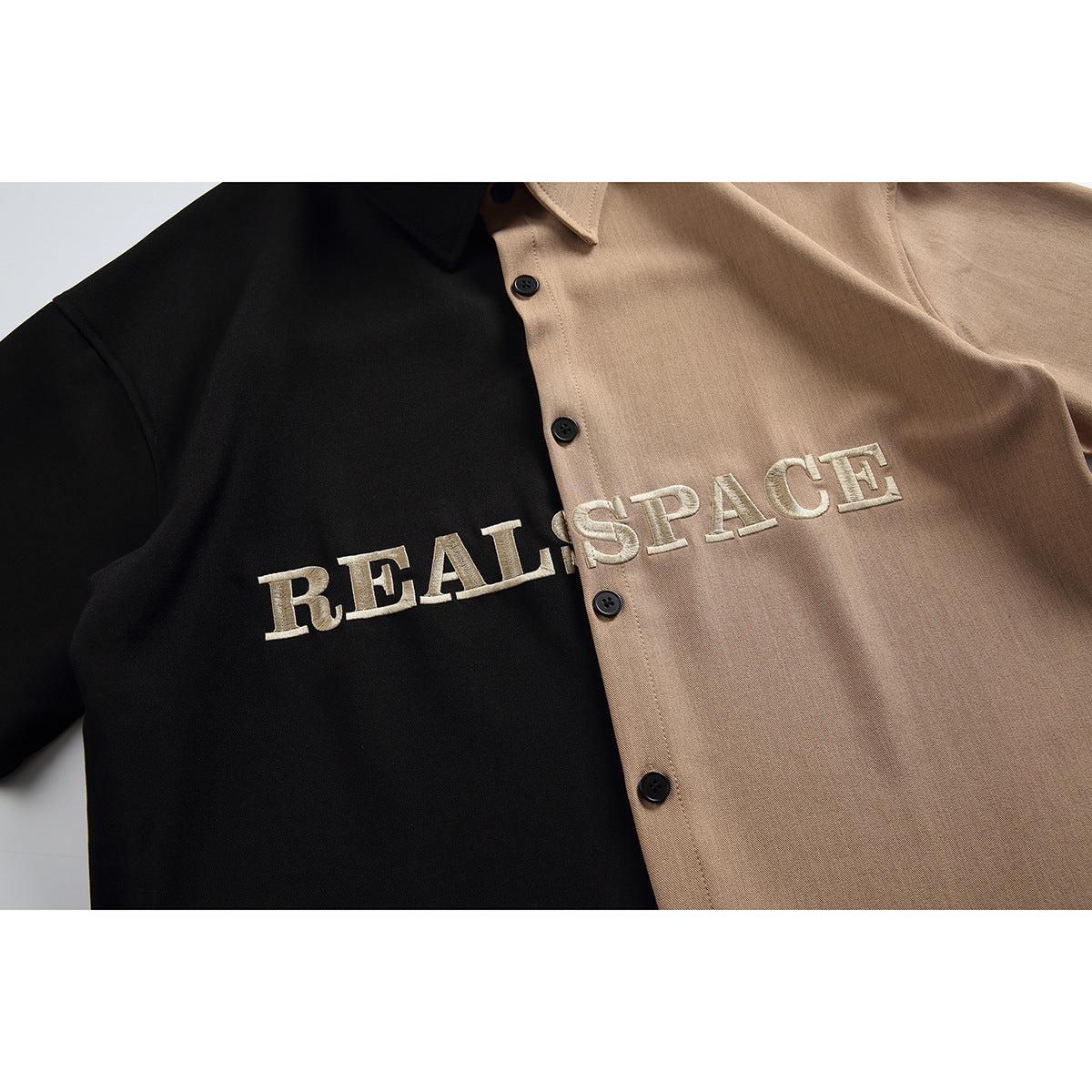 Close-up of black and tan shirt fabric, buttons, and raised cream lettering across the color-blocked front.