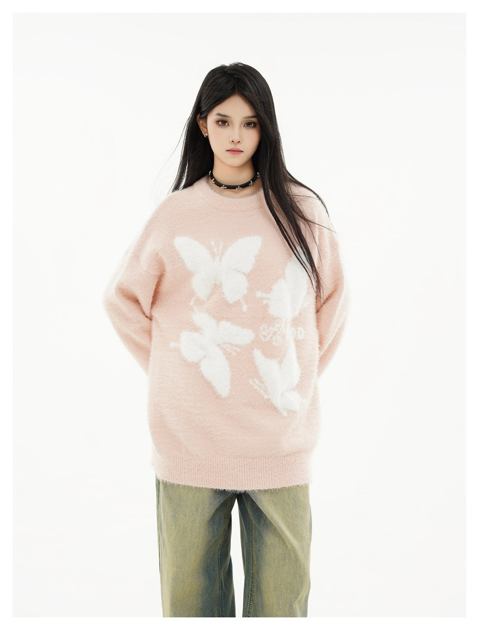 Model wearing an oversized pale pink sweater with white butterfly motifs and loose jeans, front view.
