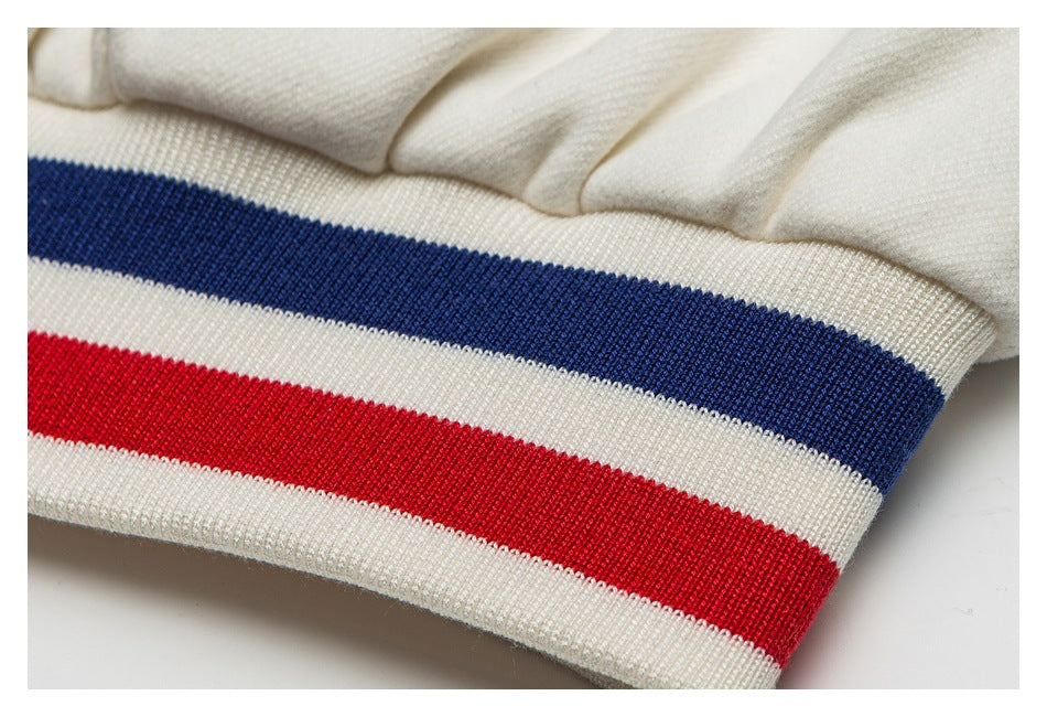 Close-up of an ivory ribbed garment band with navy and red horizontal stripes.