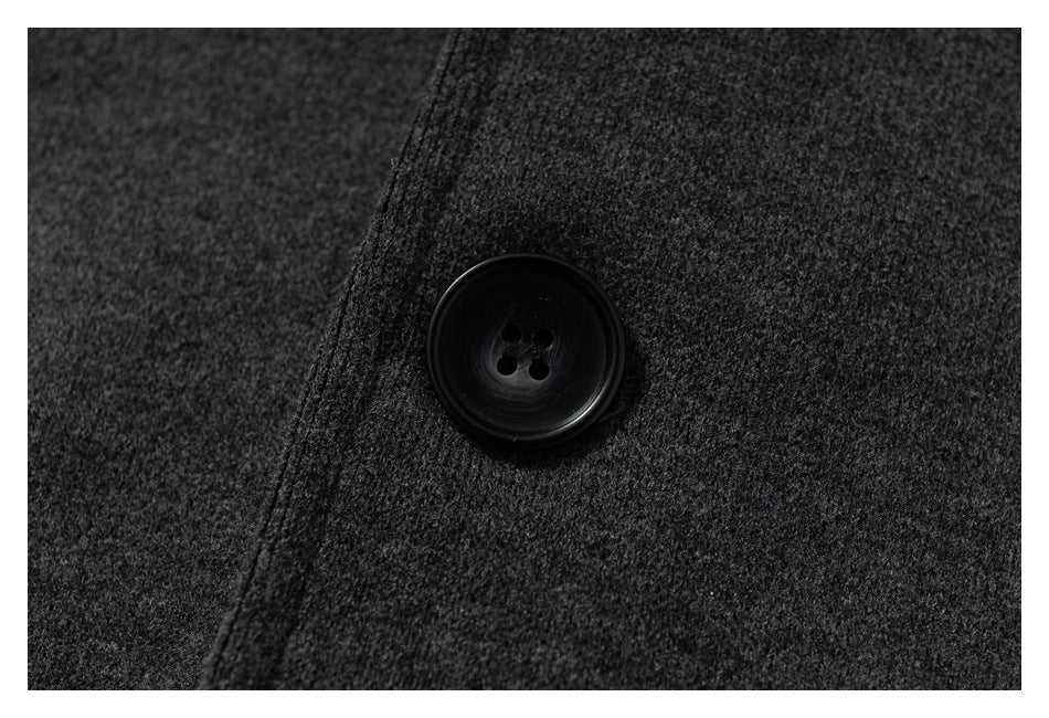 Close-up of a black four-hole button on charcoal textured fabric.