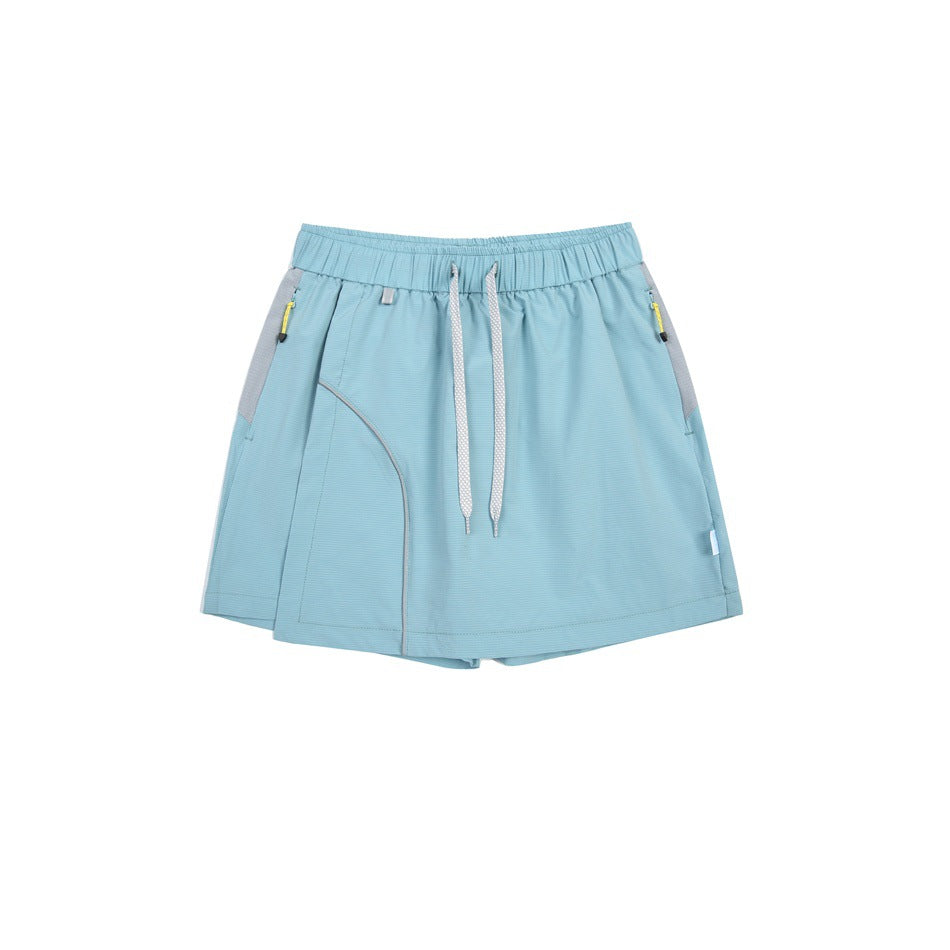 Front view of a light blue athletic skort with an elastic drawstring waist, gray side panels, and zip pockets.