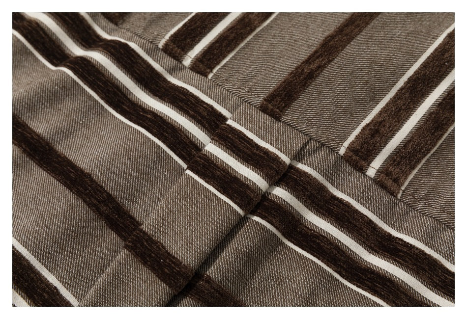 Close-up of a stitched placket on taupe fabric with dark brown and cream stripes.