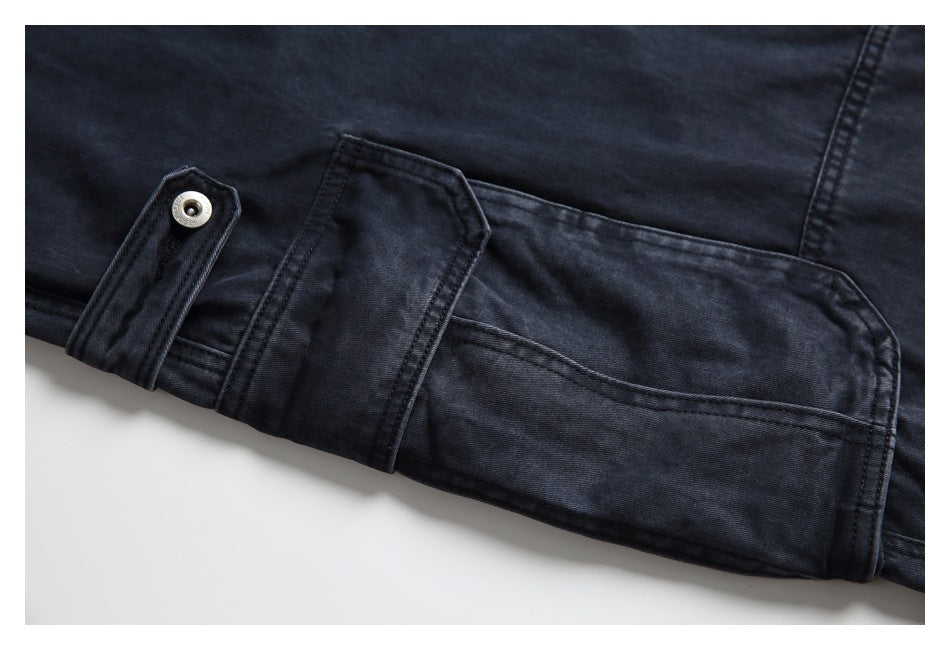 Close-up of a dark charcoal jeans leg with a buttoned adjustment tab and stitched panel.