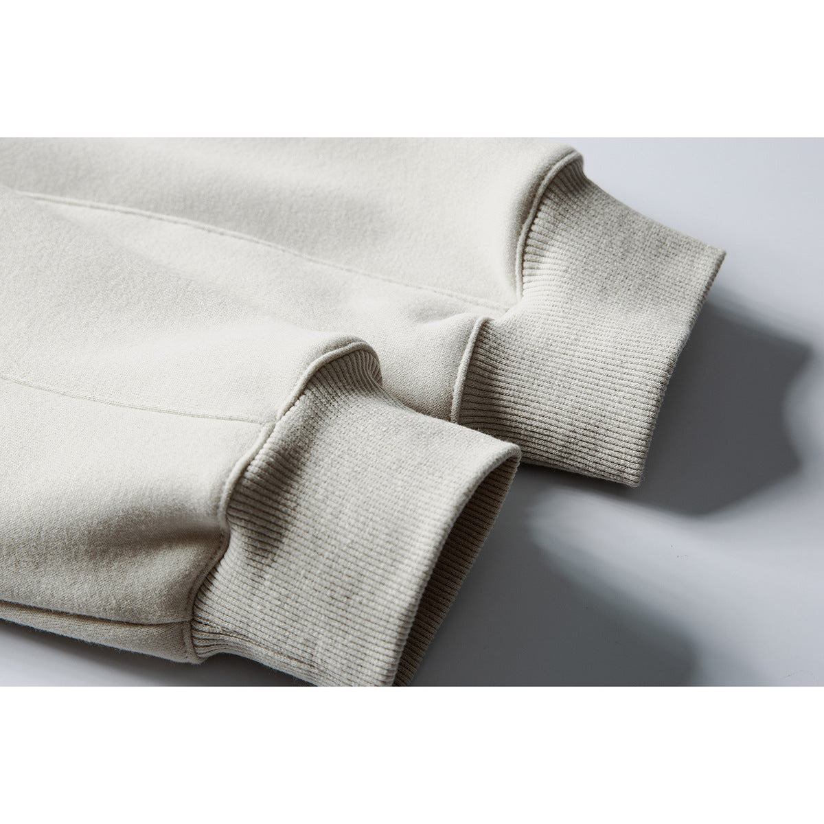 Close-up of the ribbed cuffs and seam details on an off-white sweatshirt.