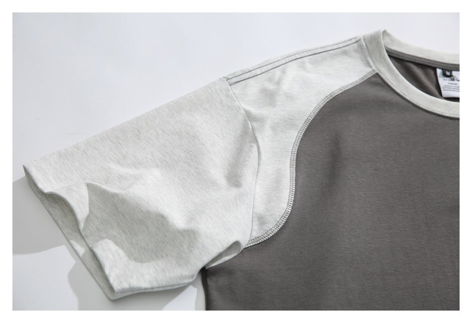 Close-up of a light heather-gray raglan sleeve and curved stitched seam against the charcoal shirt body.