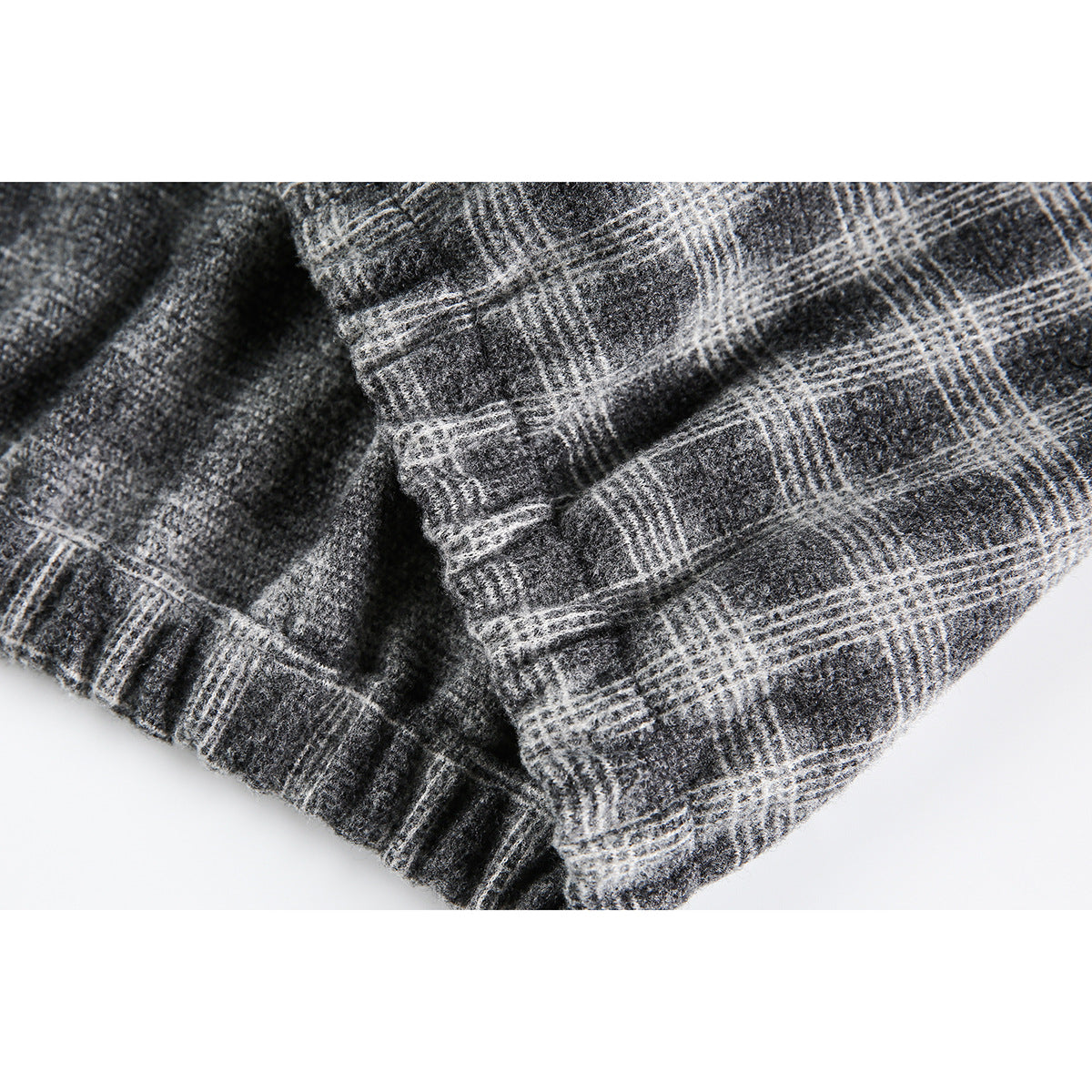 Close-up of gray plaid fabric and a gathered edge at the jacket cuff or hem.
