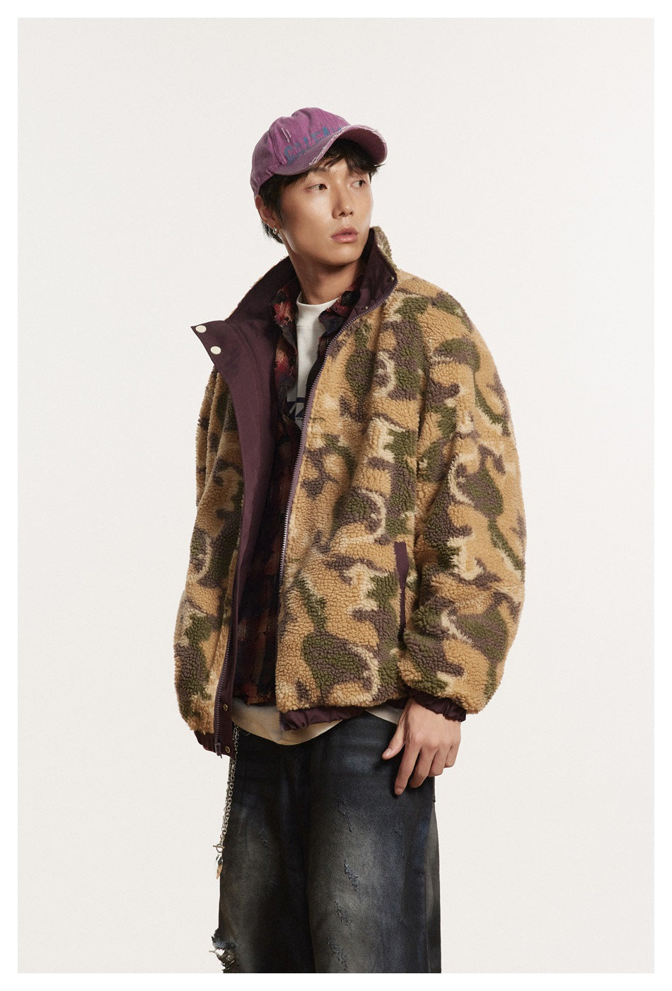 Model wearing a tan, olive, and brown camouflage fleece jacket with plum trim and dark jeans.