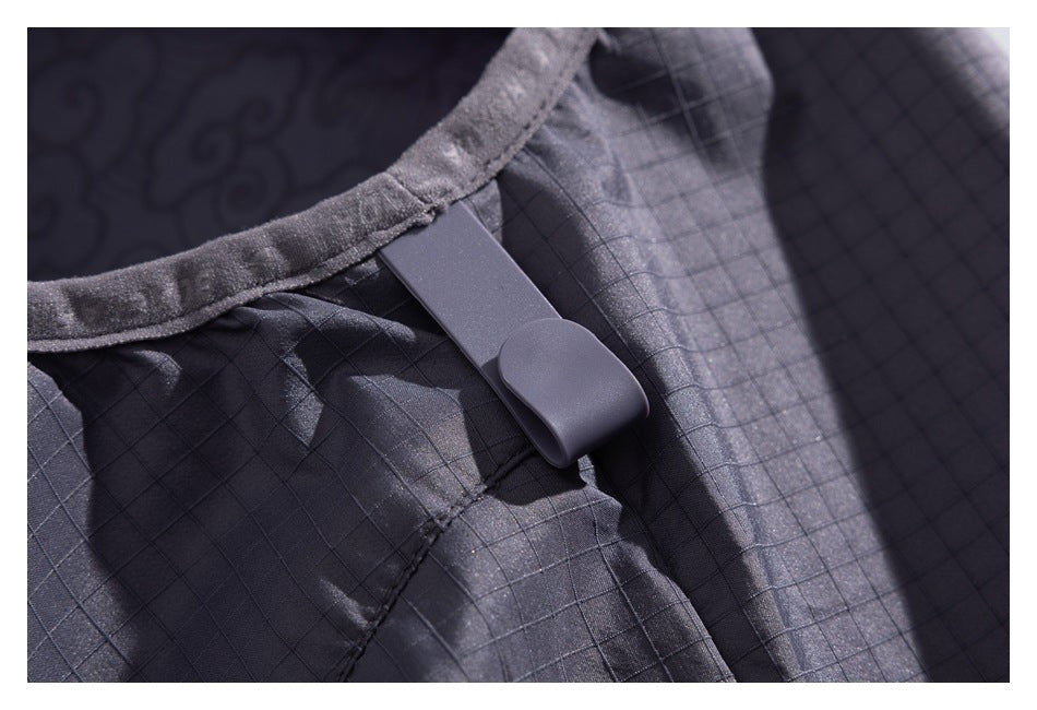 Close-up of a small gray hanging loop attached to the seam of a charcoal grid-patterned jacket.