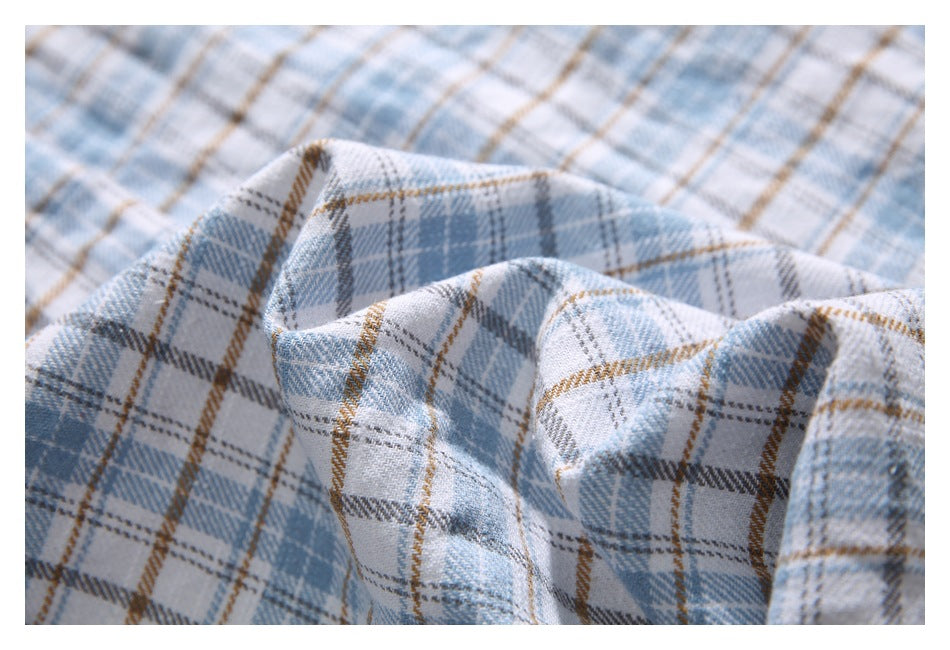 Close-up of pale blue, white, gray, and tan plaid fabric arranged in soft folds.