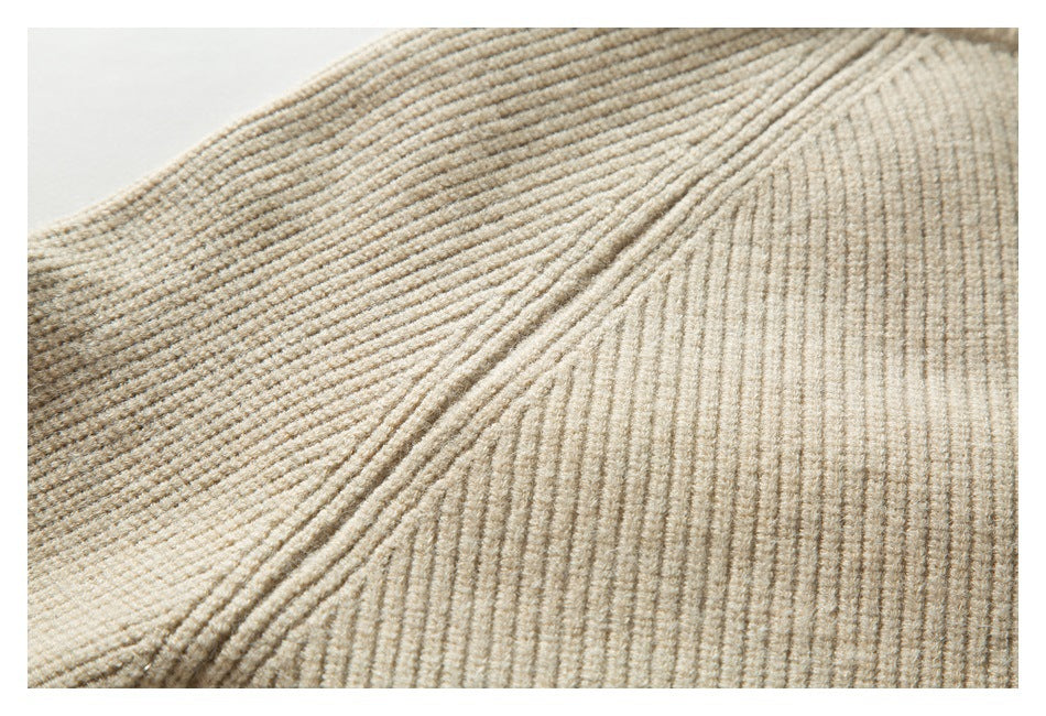 Close-up of beige rib-knit fabric with diagonal folds and pronounced vertical ridges.