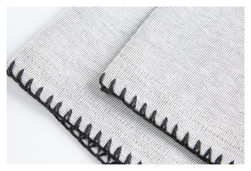 Close-up of light gray garment edges finished with thick black blanket stitching.