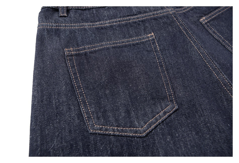 Close-up of a rear pocket on dark indigo jeans, outlined with tan contrast stitching.