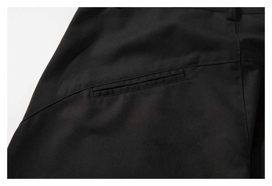 Close-up of a black trouser back pocket and surrounding diagonal seam.