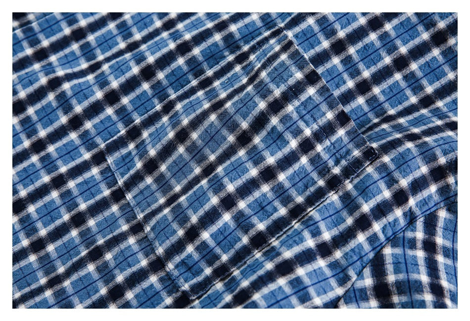Close-up of a rectangular pocket and stitching on blue, navy, and white plaid fabric.