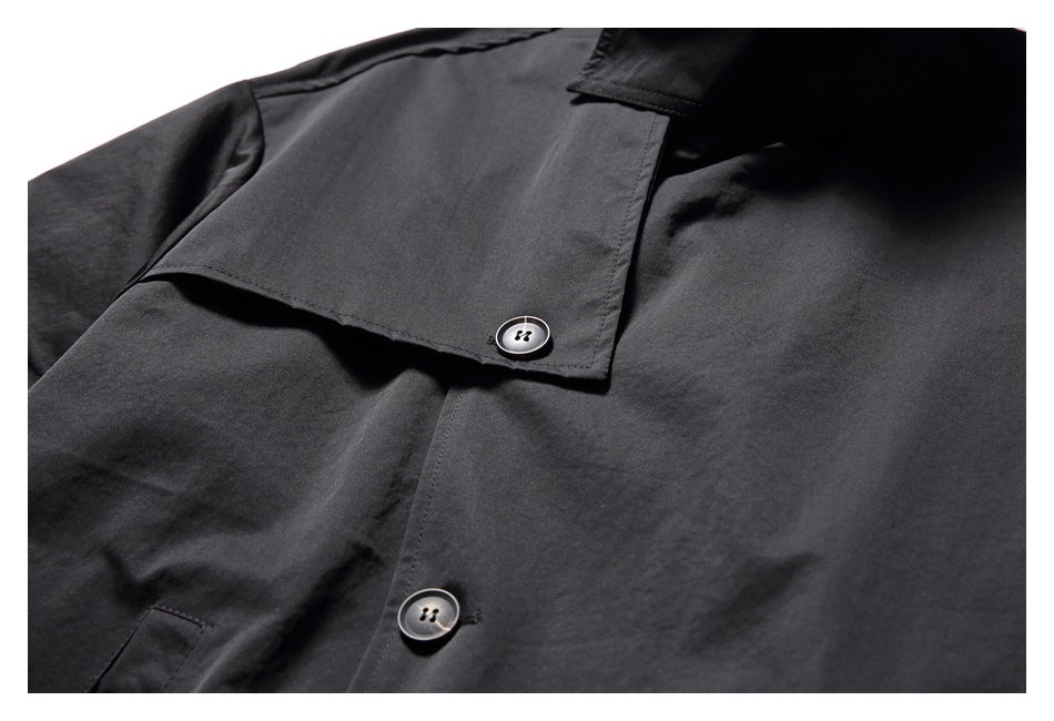 Close-up of a black collared garment showing a flap, front buttons, and stitching.