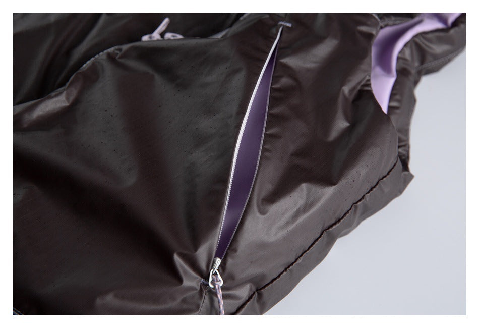 Close-up of a dark jacket's long zipper with a purple panel and corded zipper pull.