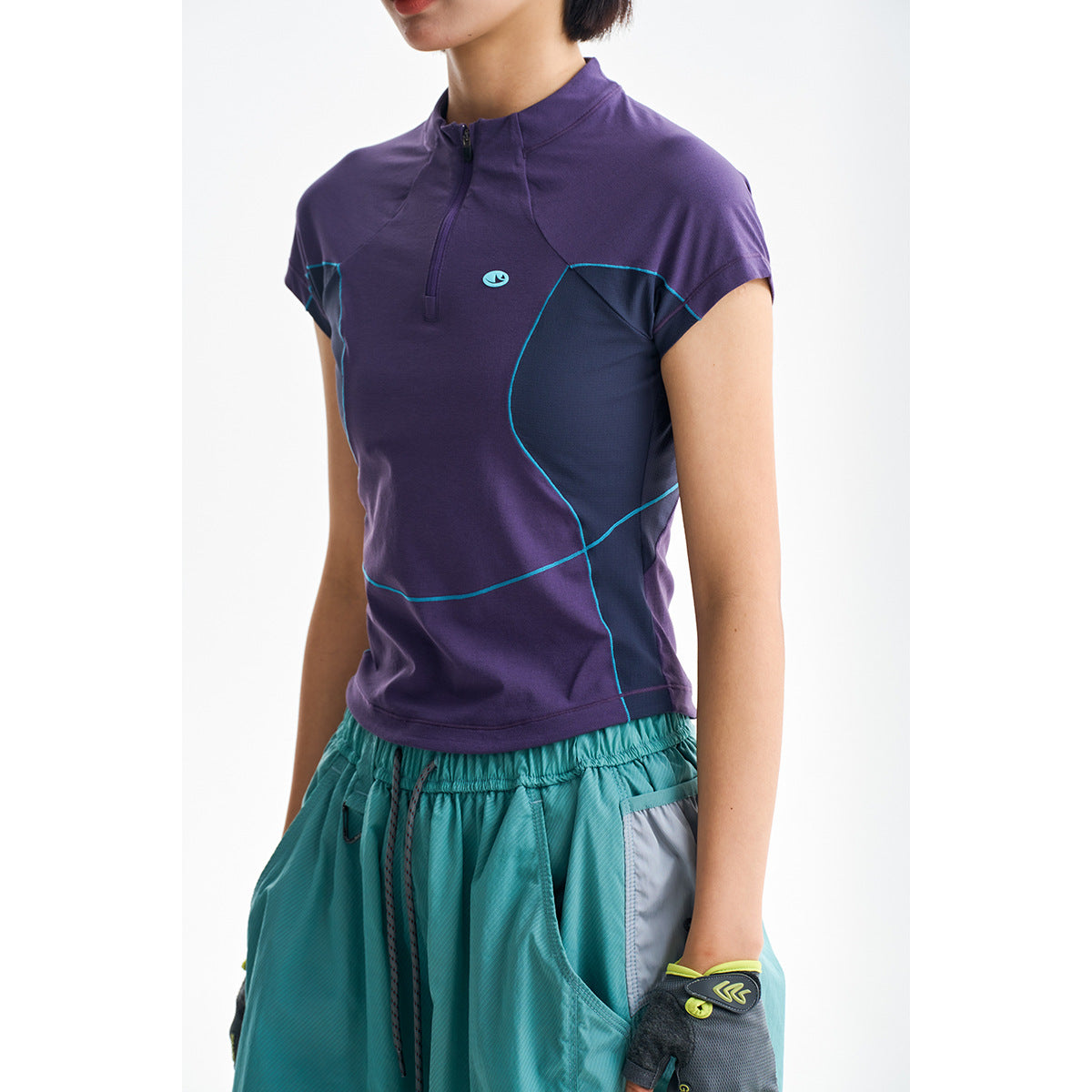 Close view of a model wearing a purple quarter-zip top with navy panels and turquoise piping.