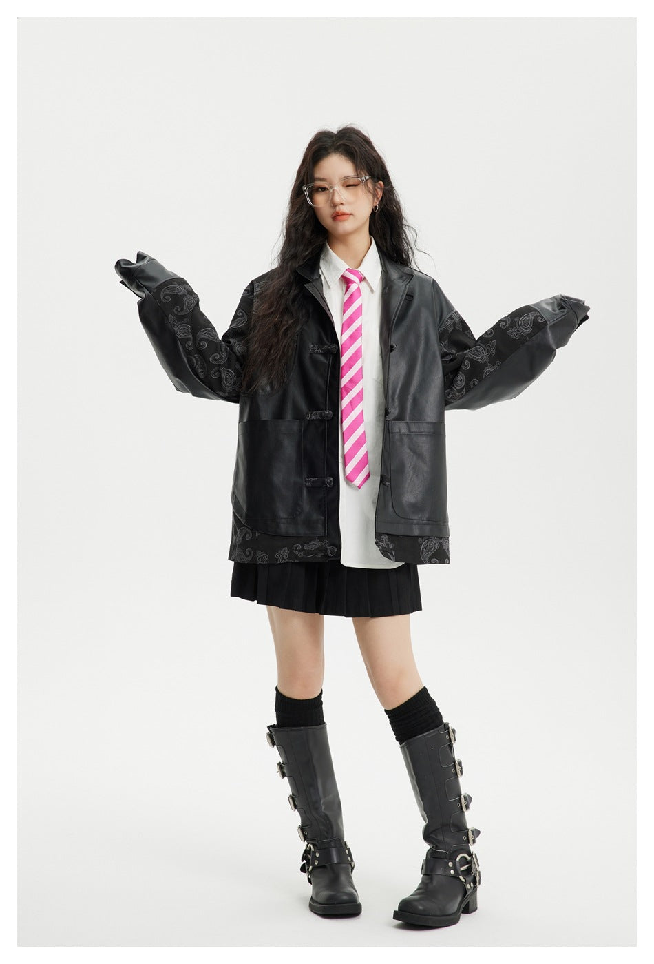 Model with arms outstretched showing the black paisley-sleeve faux-leather jacket worn open with boots