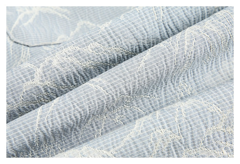 Macro view of pale blue and off-white woven fabric with raised mountain-pattern details.