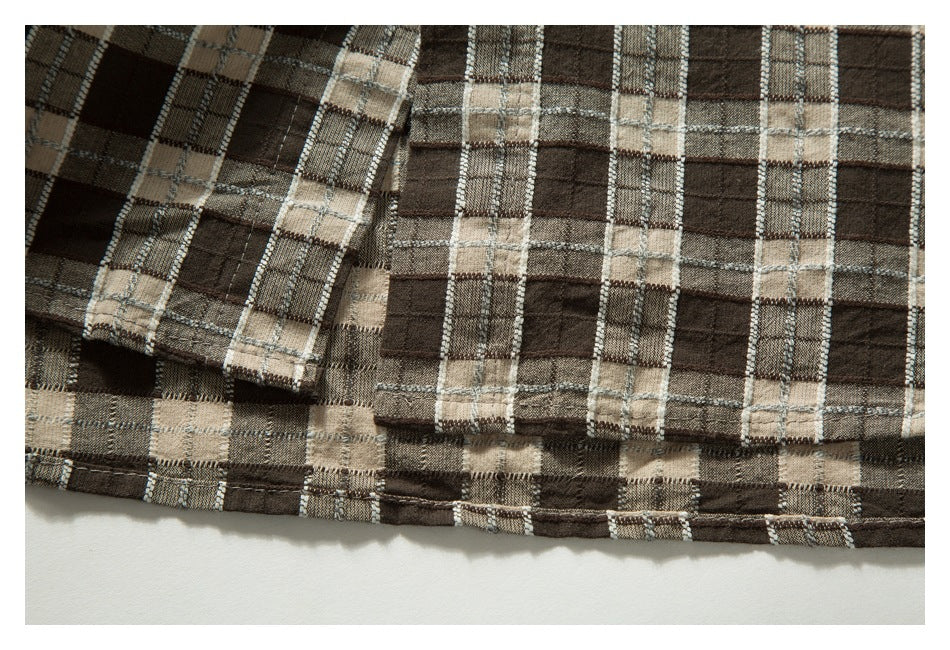 Close-up of a brown, beige, and gray plaid garment hem with stitched edges.