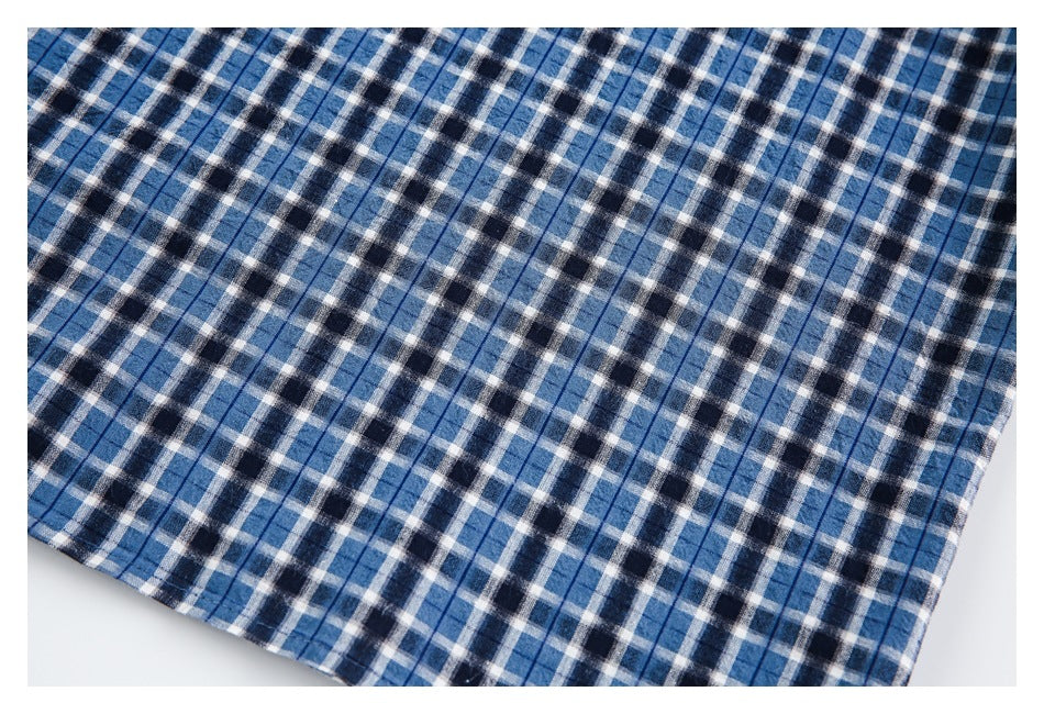 Close-up of blue, navy and white plaid shirt fabric with intersecting checks and thin stripes.
