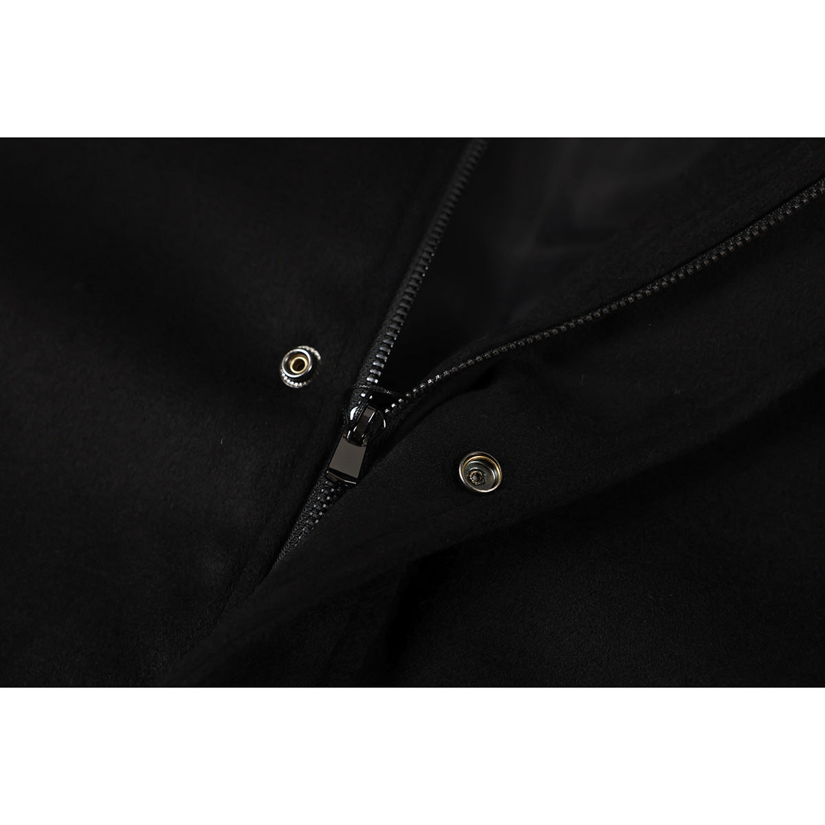 Close-up of a black jacket's zipper and metal snap fasteners.