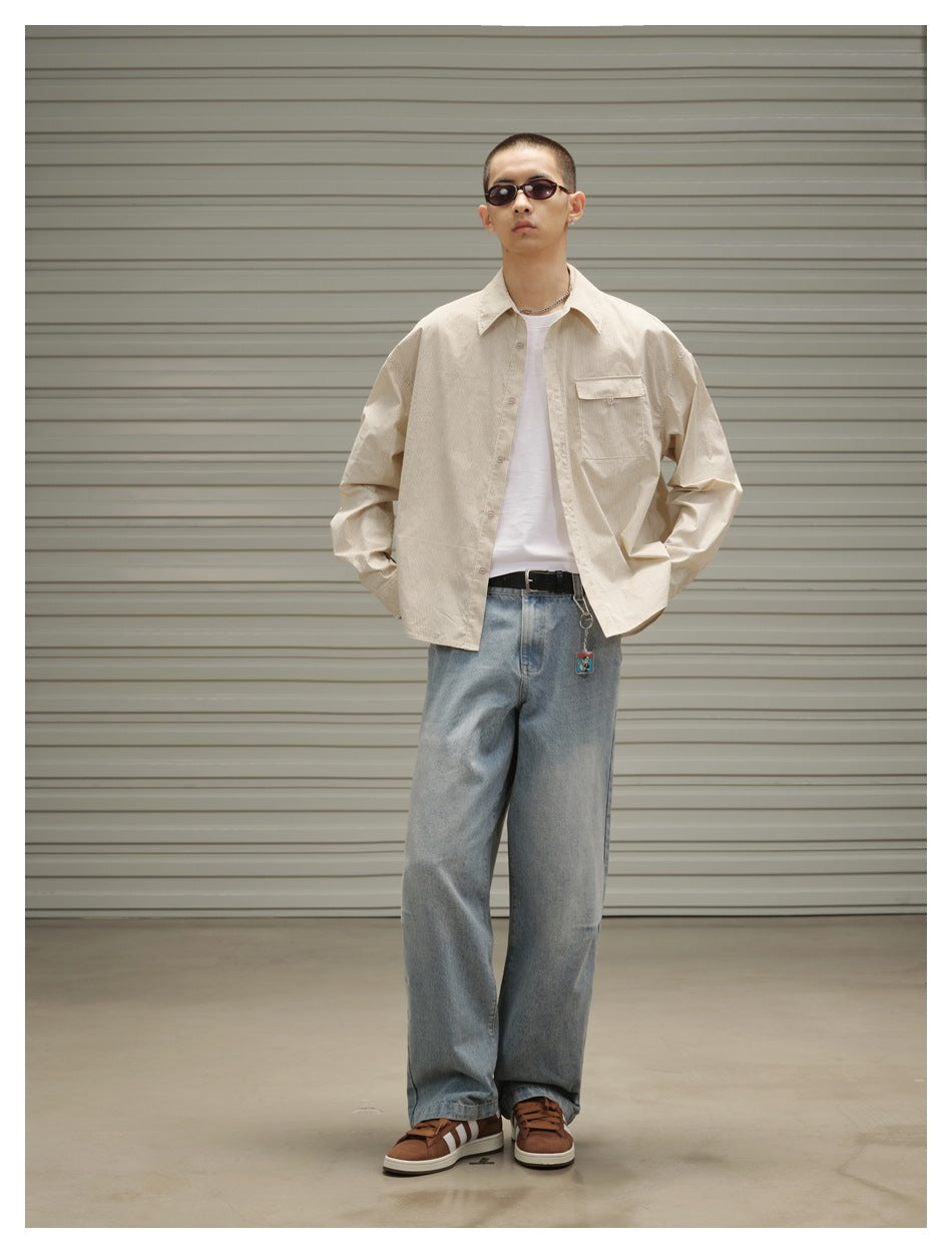 Model wearing light blue wide-leg jeans with a beige striped shirt, white tee, black belt and brown sneakers